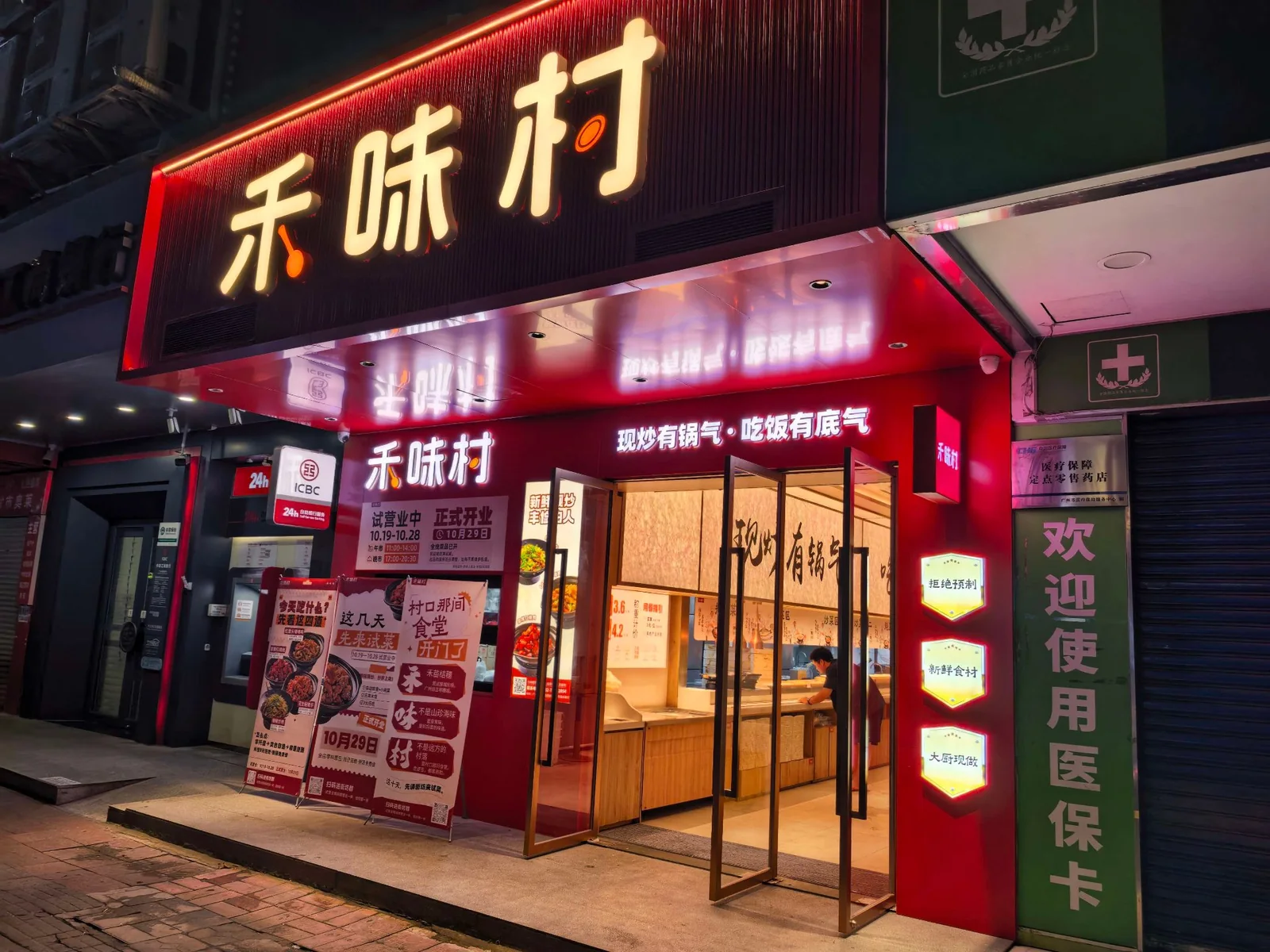 禾味村粤垦路店门头，夜里亮着红招牌，就在粤垦路 620 号路边